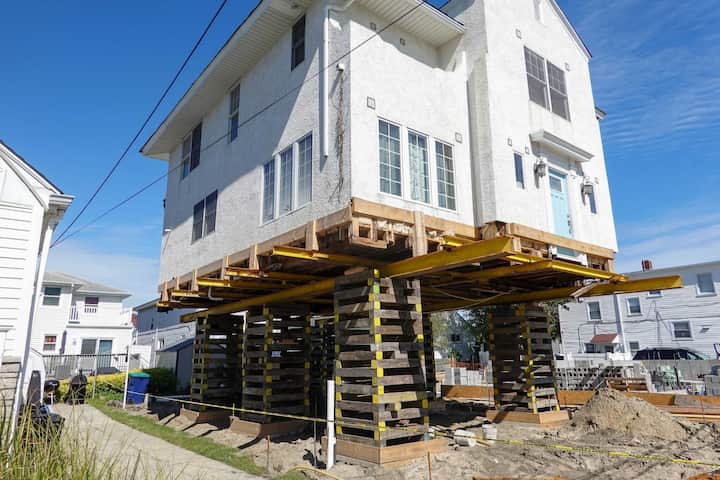 A team of professionals using specialized equipment to raise a house in New Orleans, preparing it for elevation and renovation